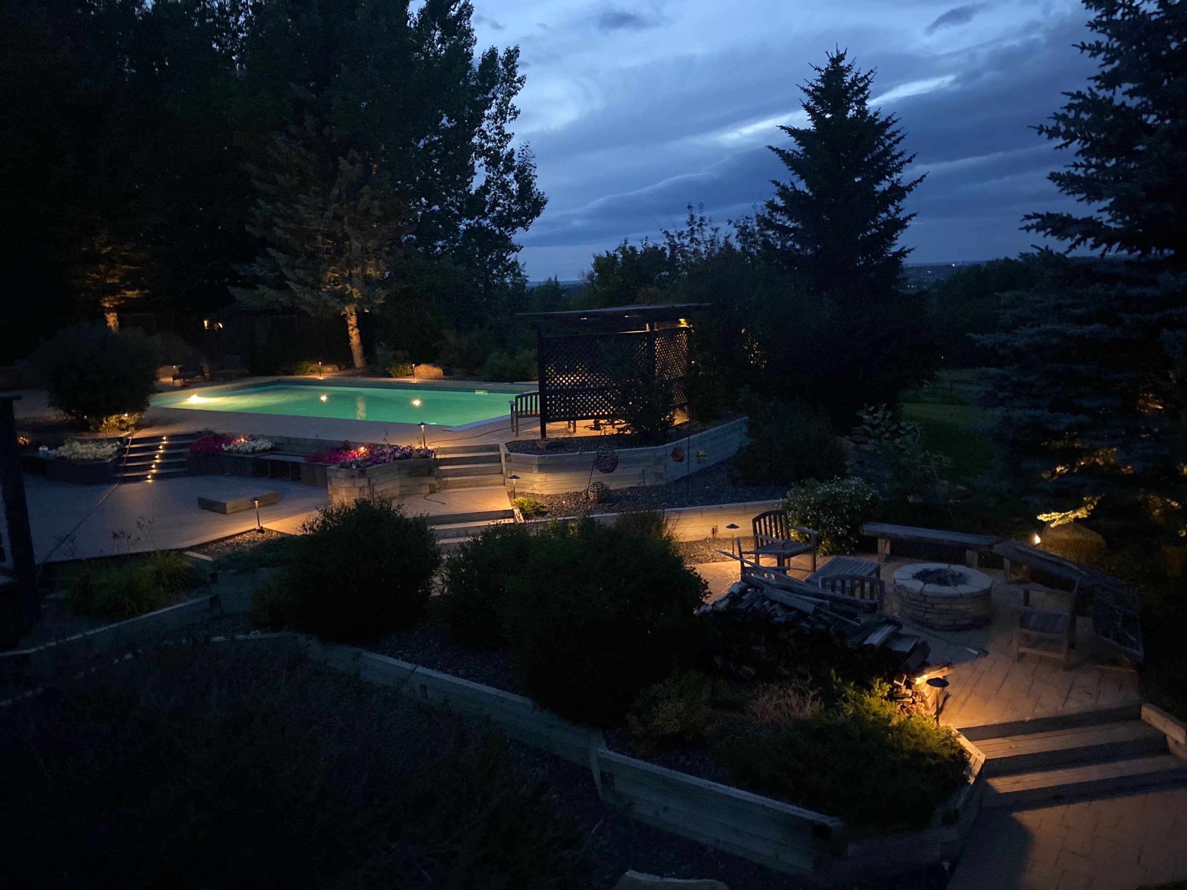 Illuminated backyard pool and patio at dusk