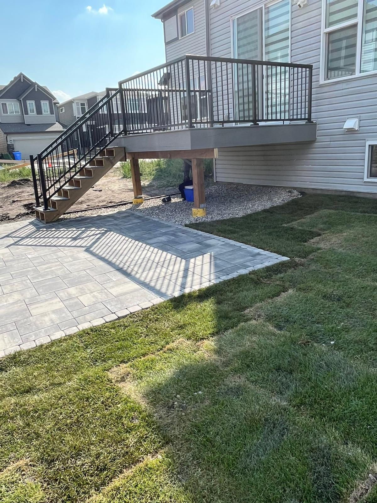 Raised backyard deck with stairs and paver patio