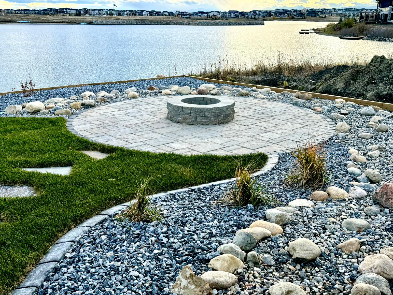 Circular stone fire pit beside lakeside backyard patio