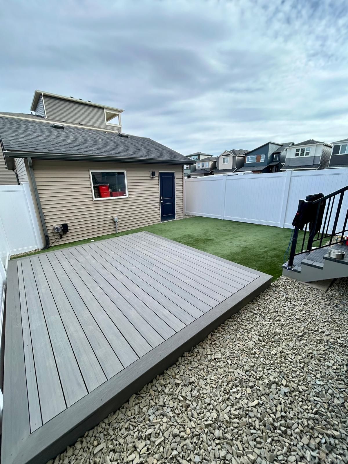 Small fenced backyard with gray deck and turf