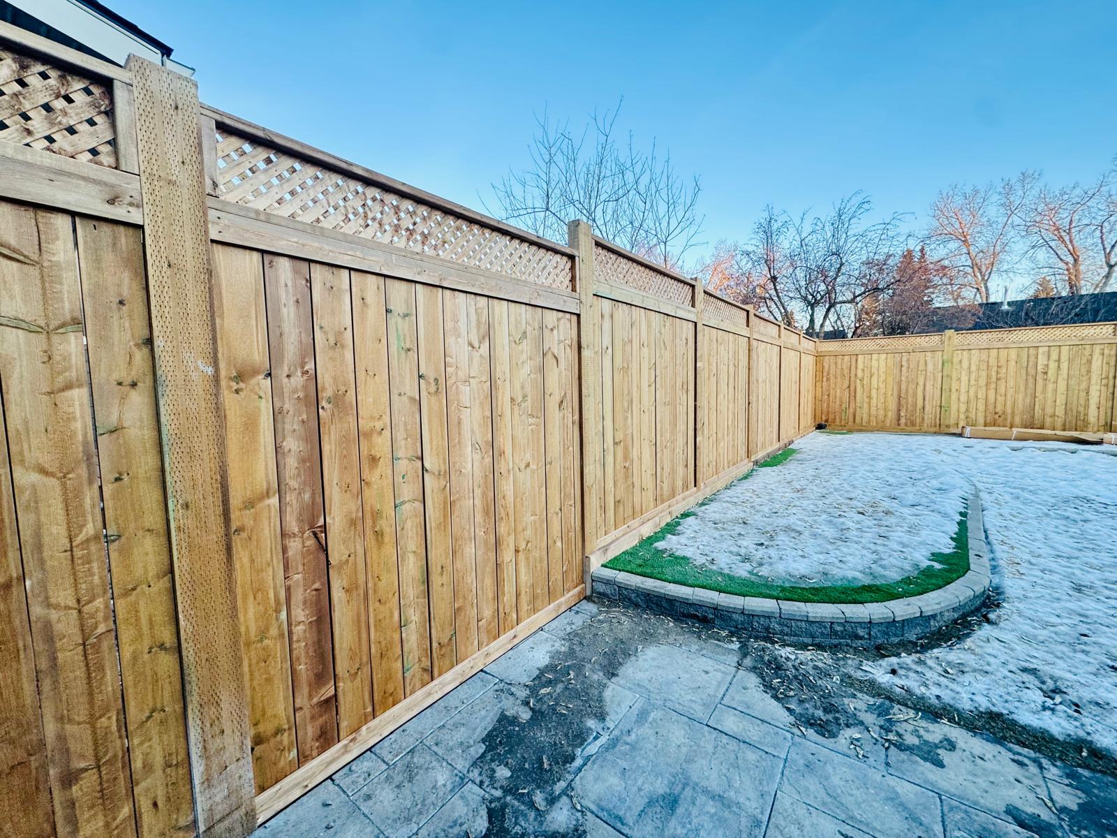 Wooden privacy fence surrounding backyard with snow