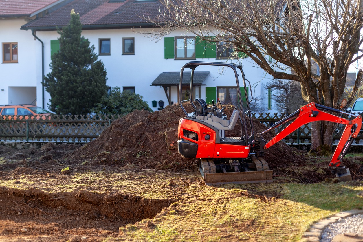 Small red excavator digging in residential backyard