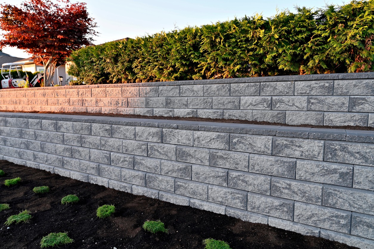 Tiered gray stone retaining wall with hedges