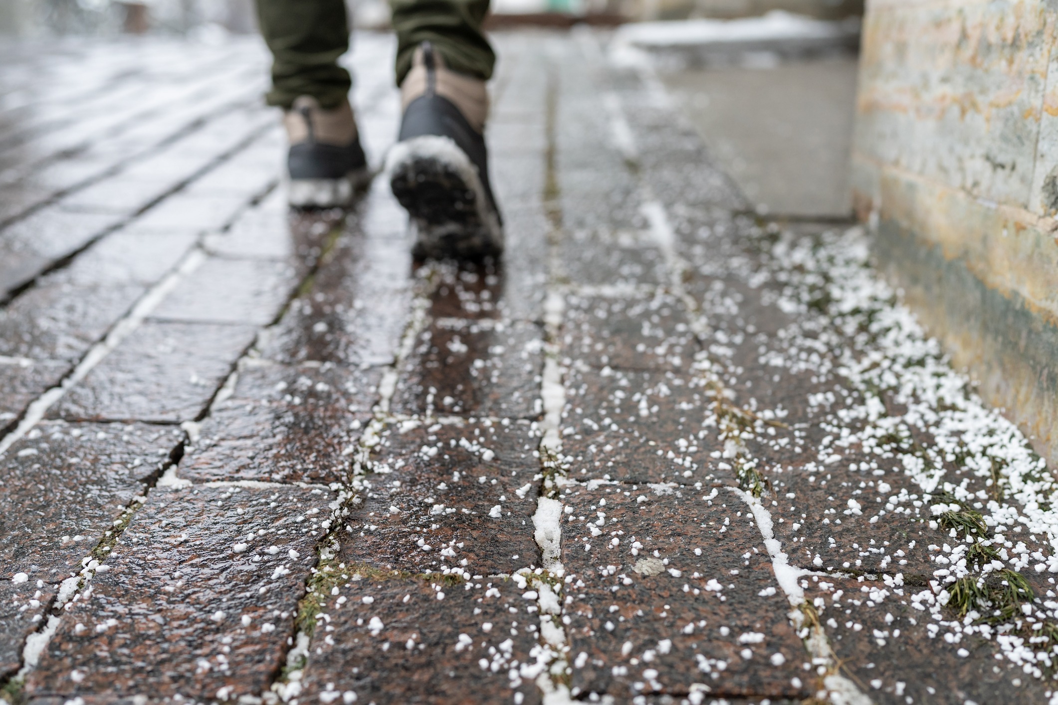 Person walking on hail-covered cobblestone street