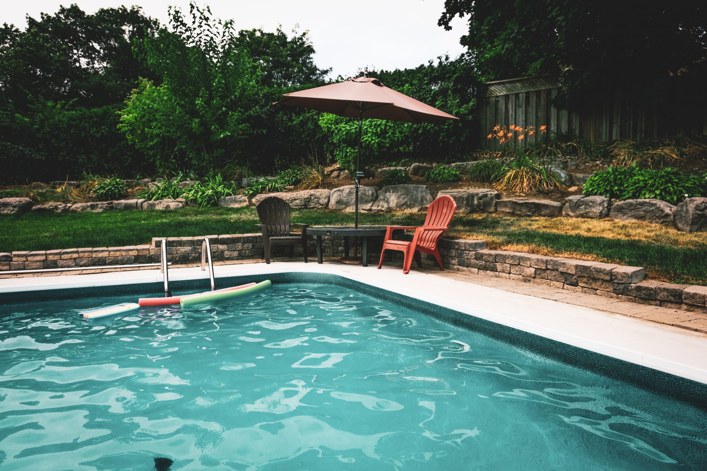 Backyard swimming pool with chairs and umbrella