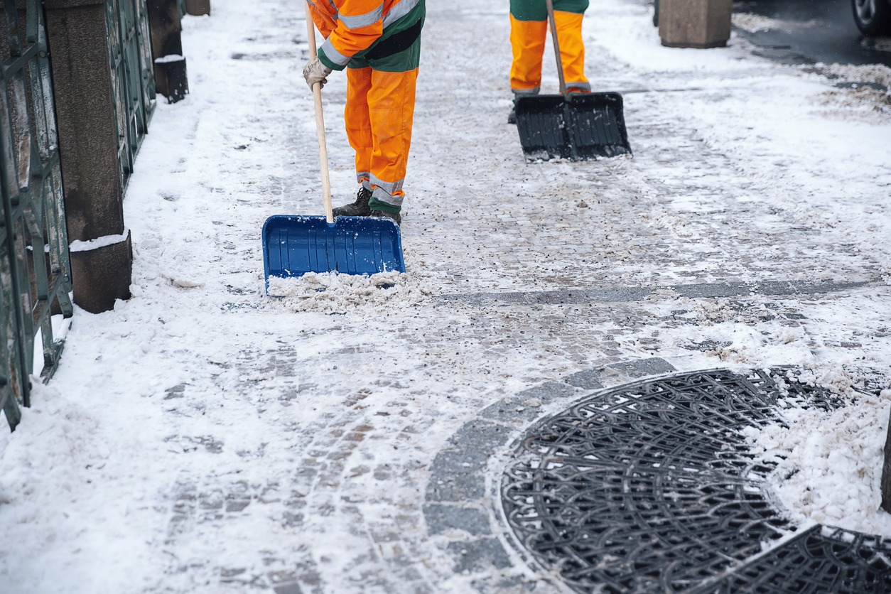 Workers shoveling snow from city sidewalk