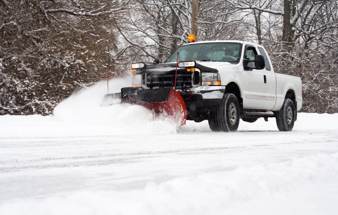White pickup truck plowing snow on winter road