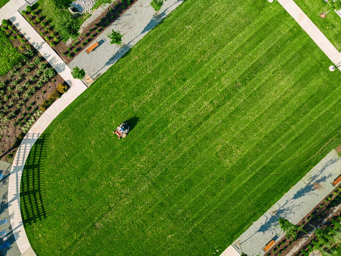 Aerial view of person mowing large green lawn