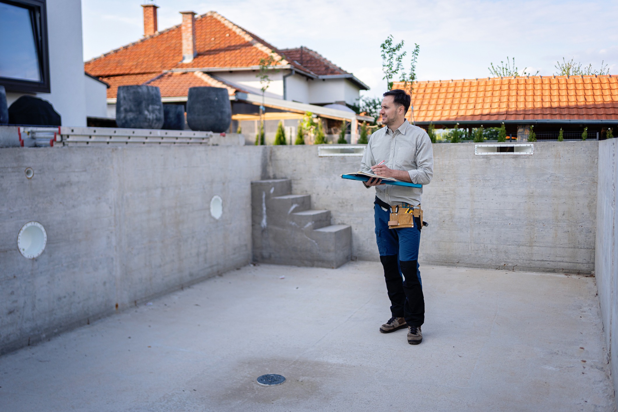 Construction inspector reviewing empty concrete swimming pool