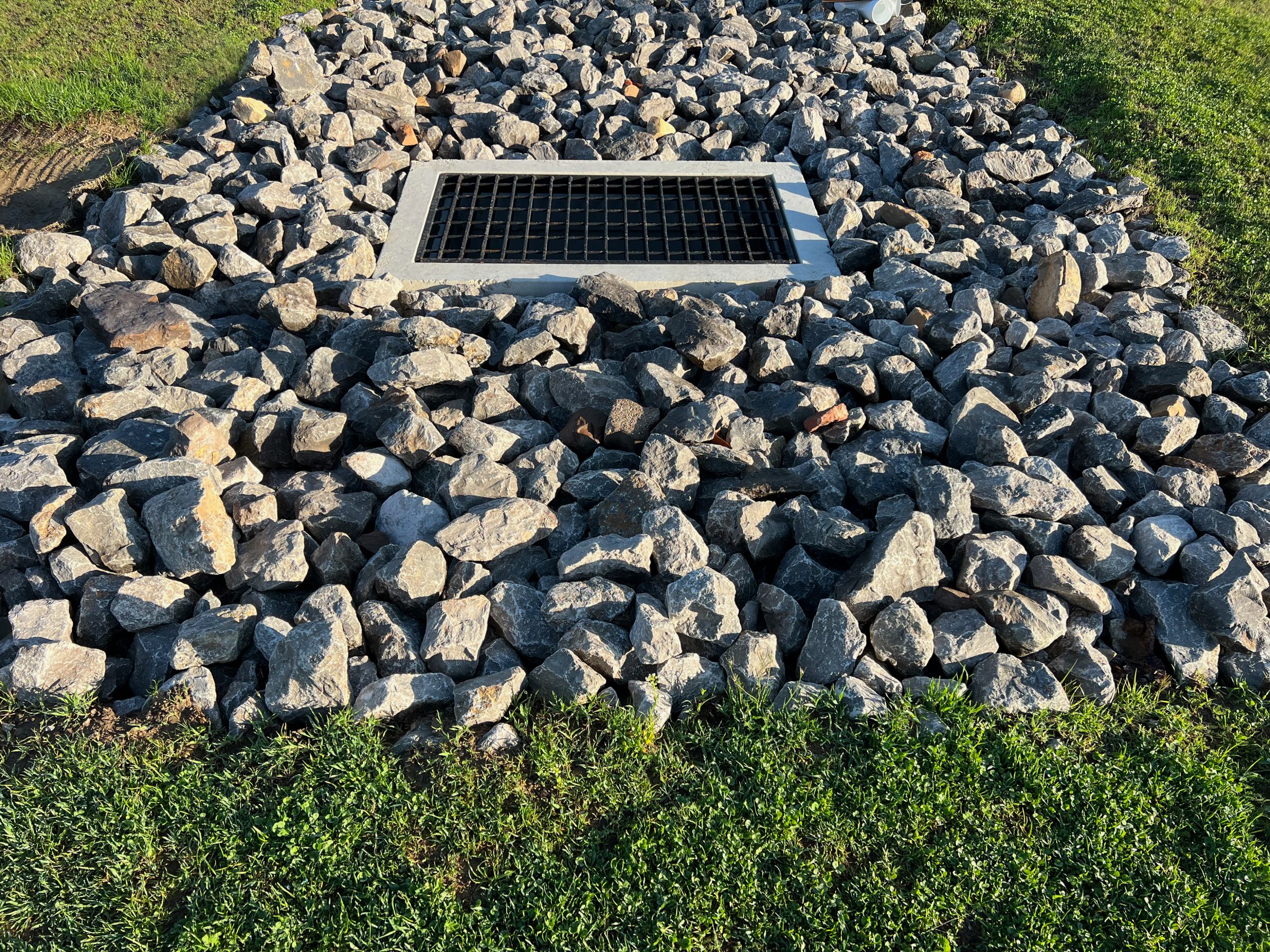 Storm drain grate surrounded by large rocks