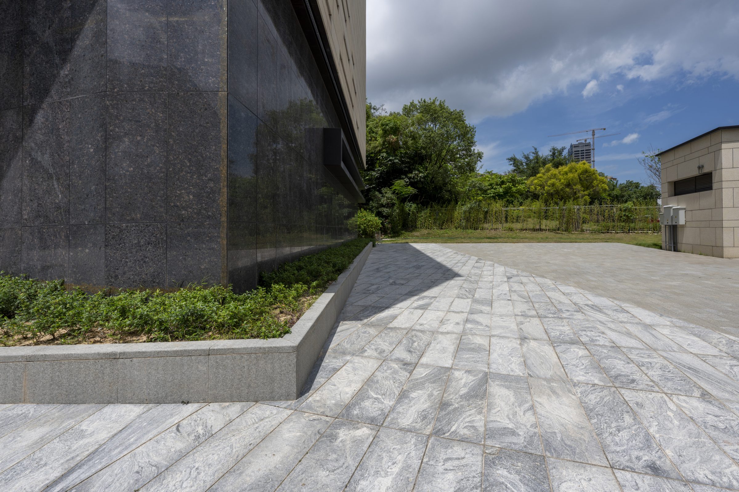Modern building exterior with tiled courtyard and greenery