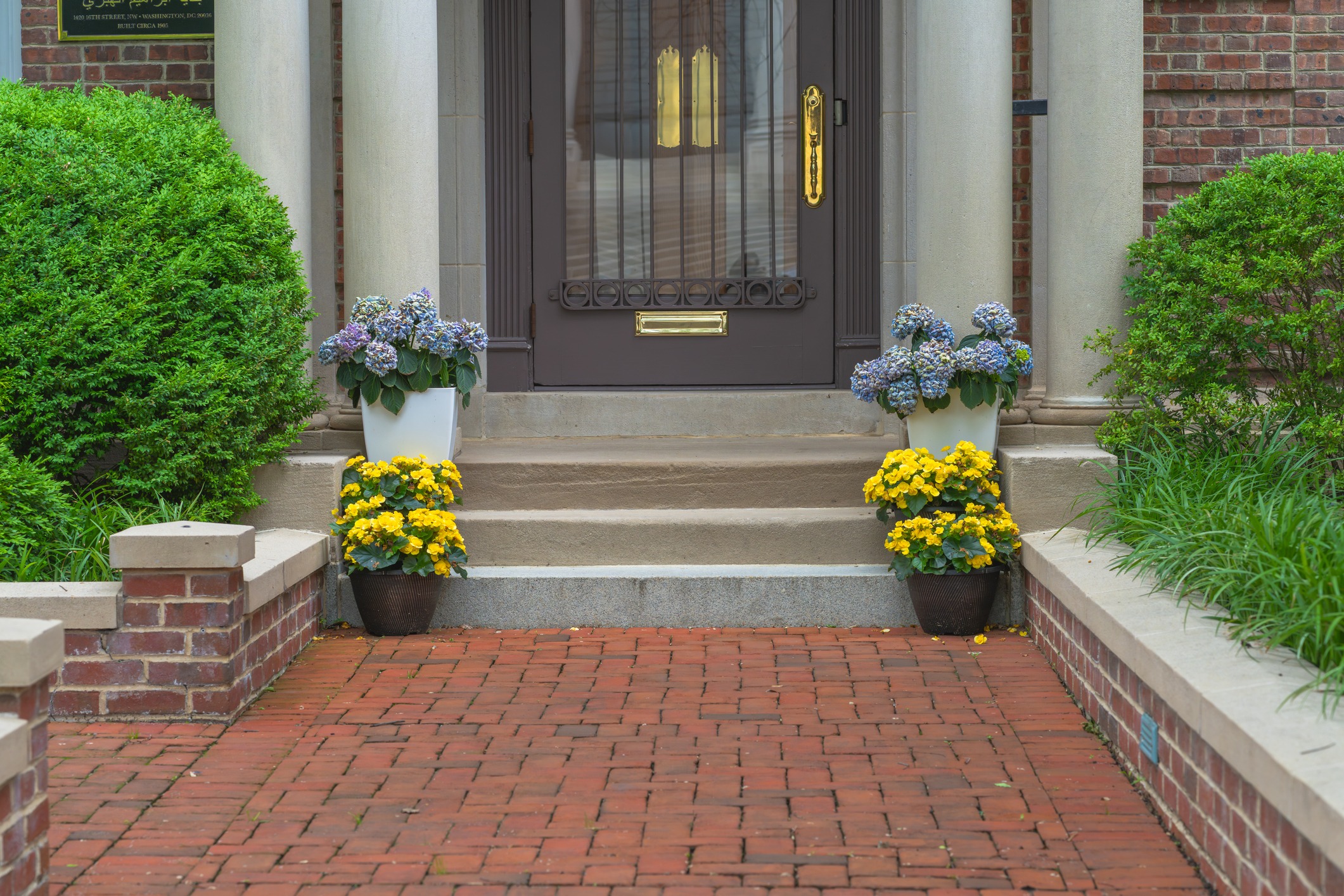 Brick walkway leading to flower-lined front door