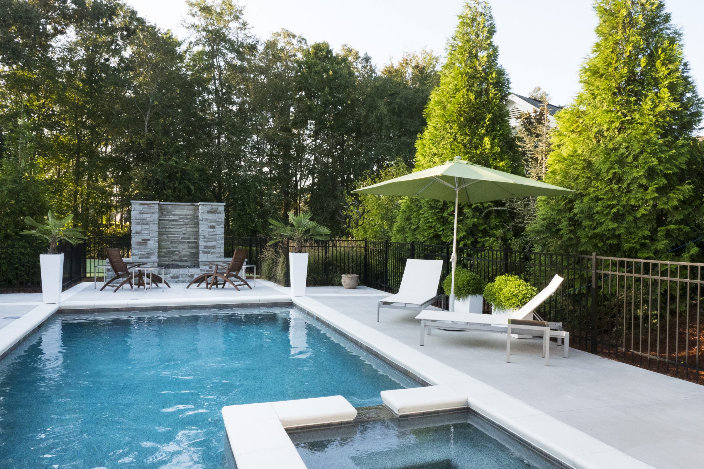 Modern backyard pool with lounge chairs and umbrella